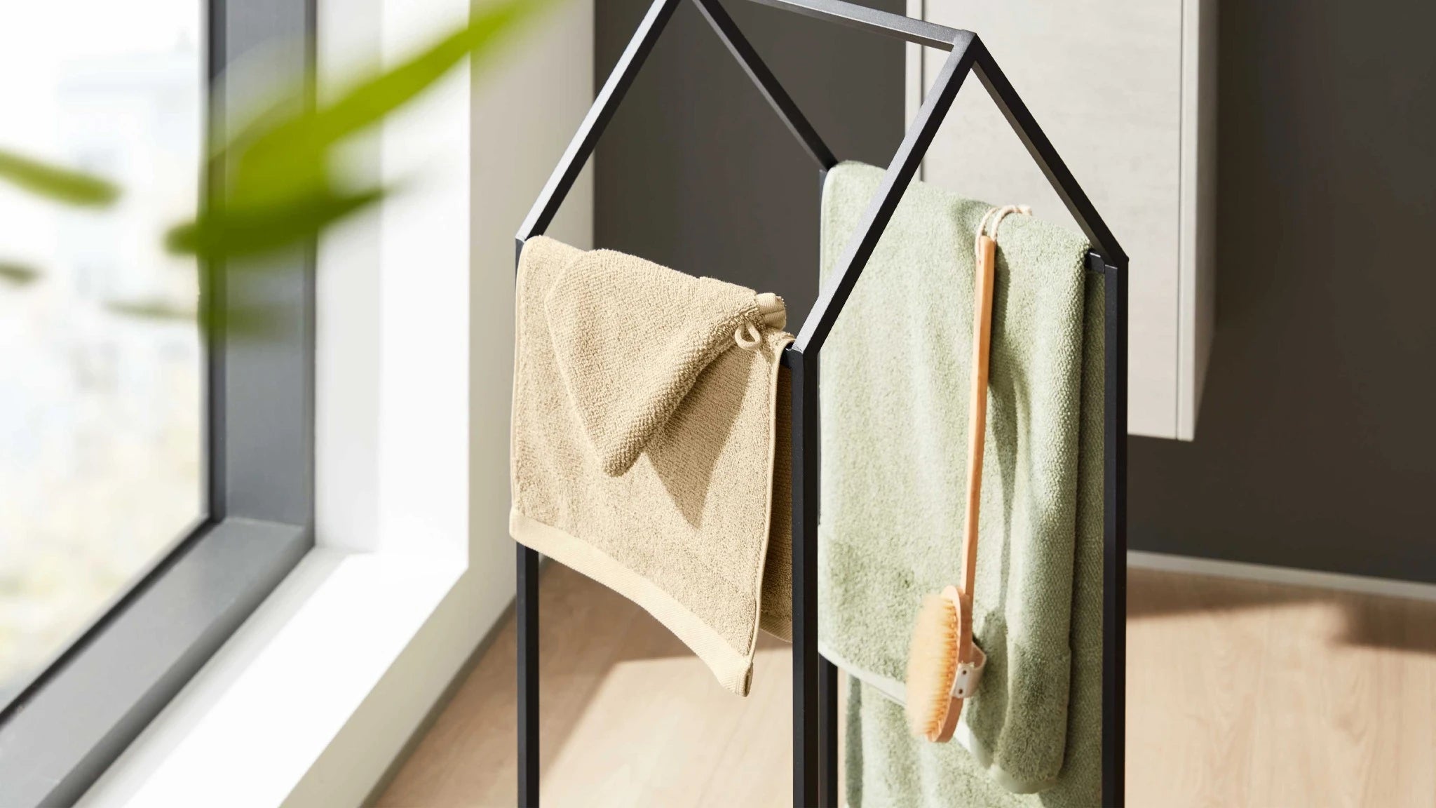 Beige und grünes Handtuch auf schwarzem Handtuchhalter im modernen Bad